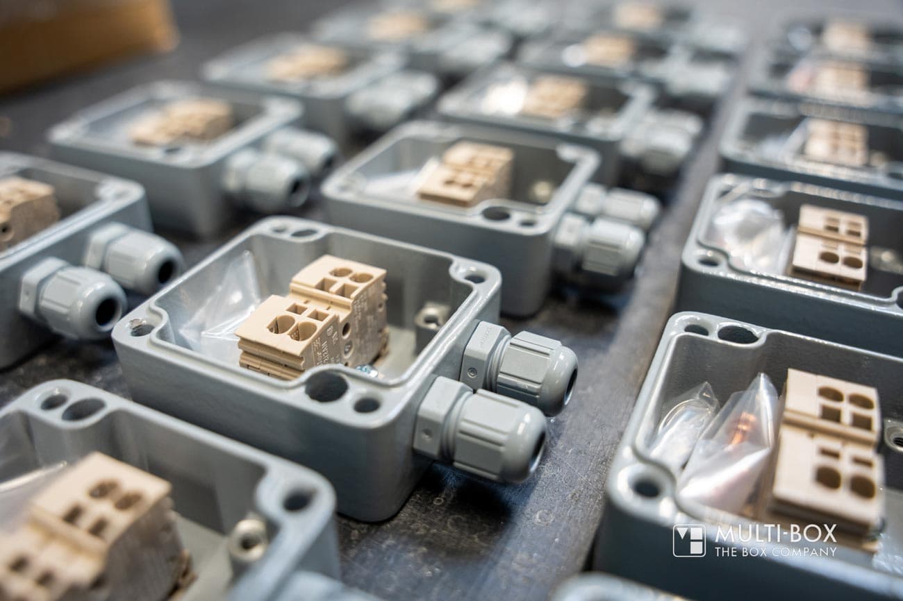 Multiple gray industrial enclosures with cable glands and terminal blocks, carefully prepared for use